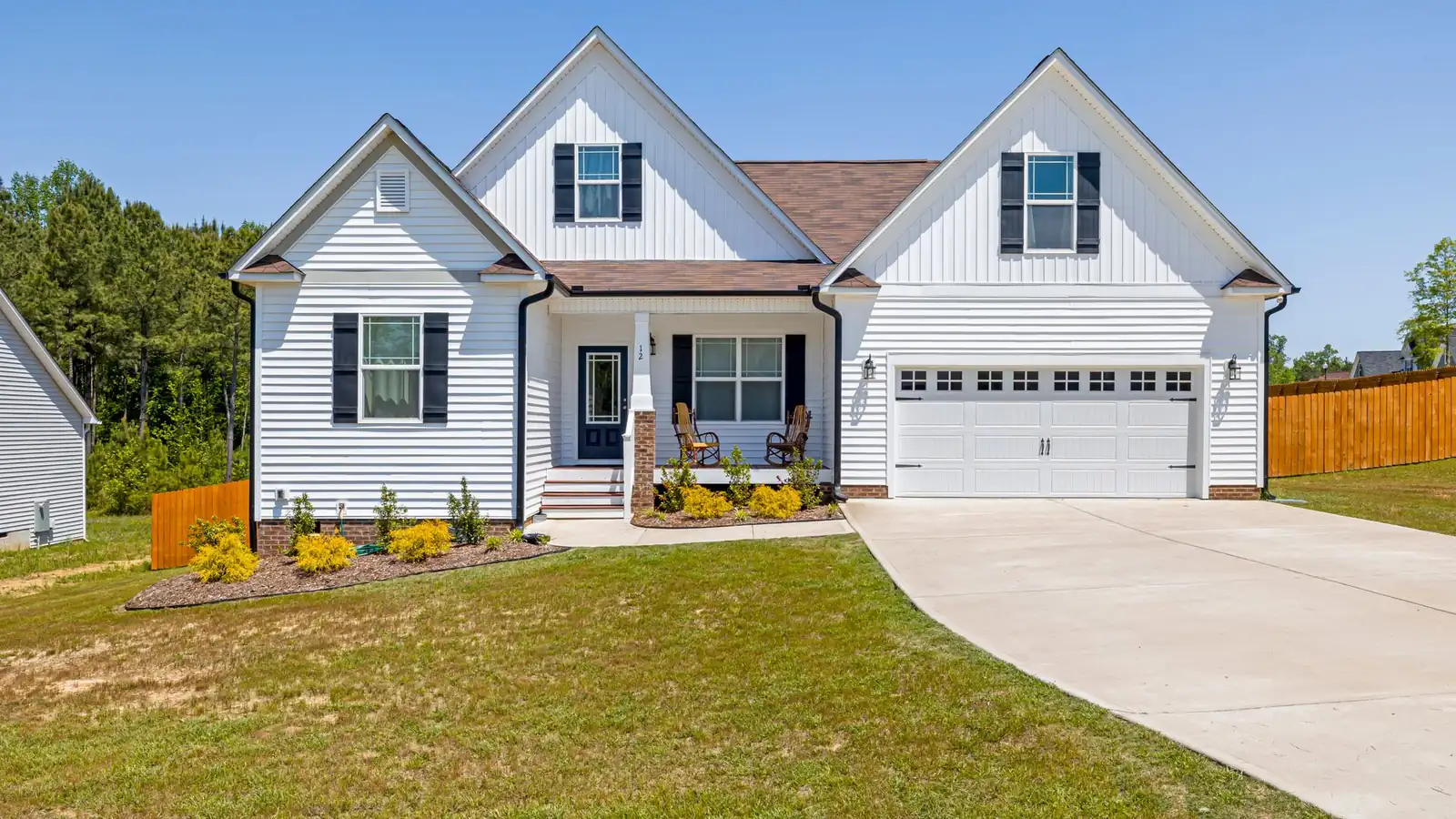 White two-story house with a wide new concrete driveway